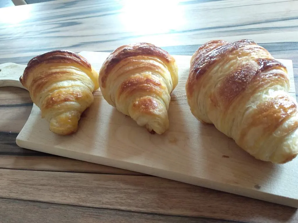 Három darab croissant péksütemény egy fa deszkán kínálva