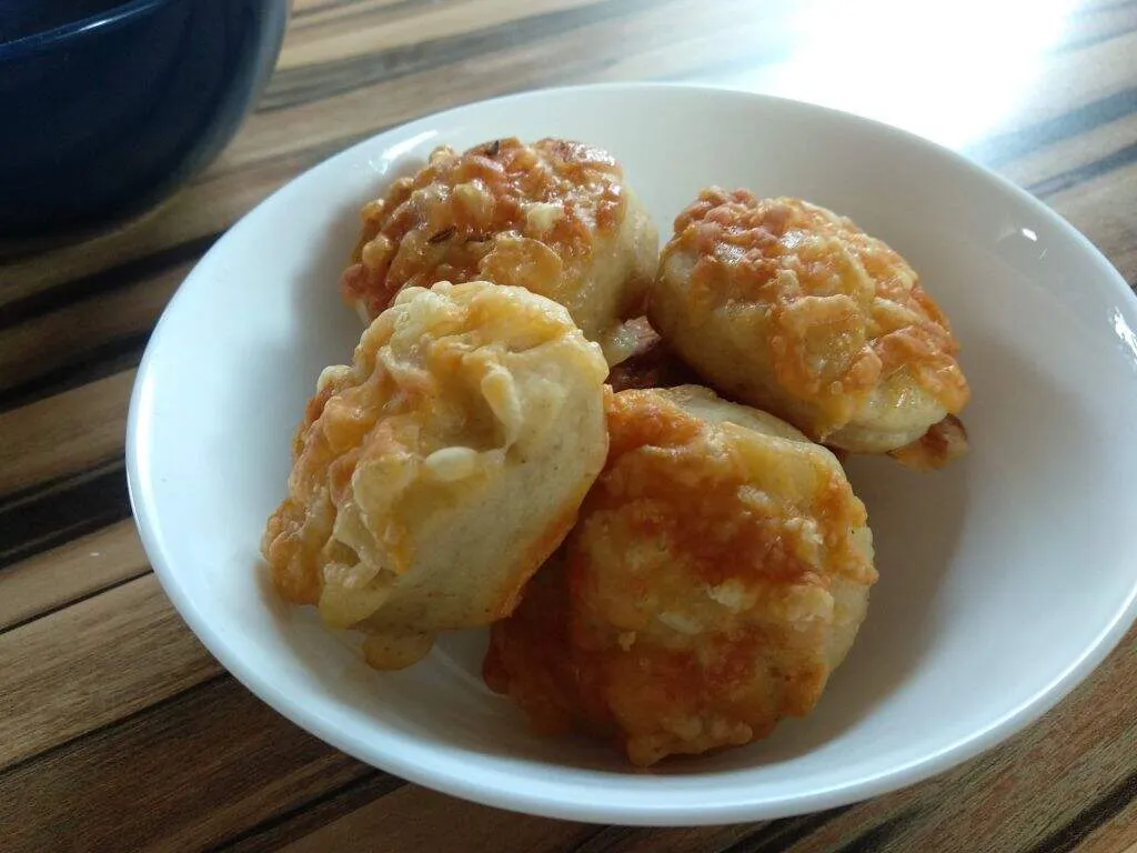 Négy darab kis pogácsa (jó sok sajttal) egy fehér tálban kínálva